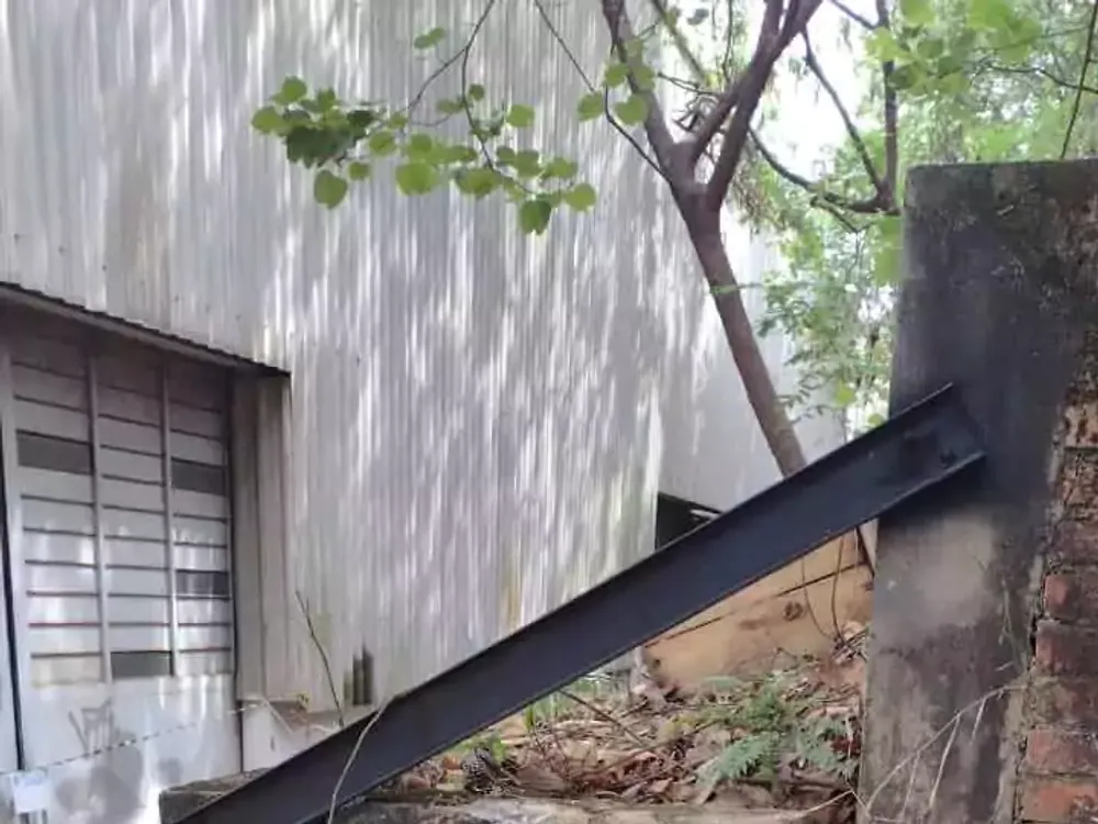 Pilar de concreto rachado na base, com viga metálica apoiada diagonalmente sobre o topo